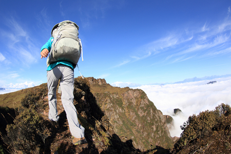young woman backpacker hiking at beautiful mountain peakの写真素材