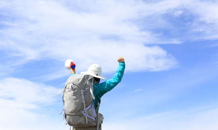 backpacker shouting with loudspeaker on beautiful mountain peakの写真素材