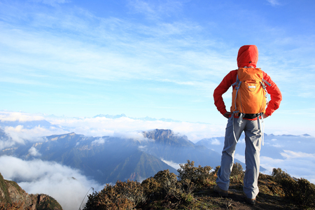 young determined woman backpacker hiking on mountain peakの写真素材