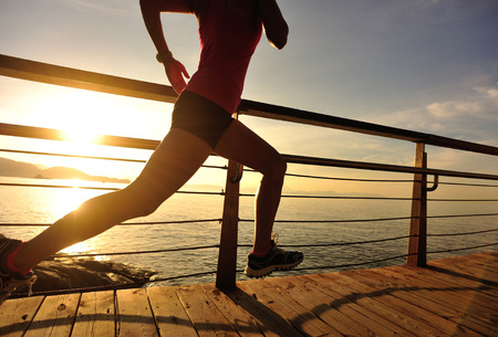 young fitness woman runner running at seaside boardwalkの写真素材