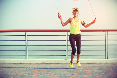 young fitness woman jumping rope at seasideの写真素材