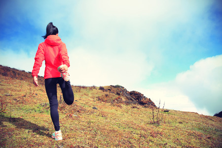 young woman trail runner warm up  on mountain peakの写真素材