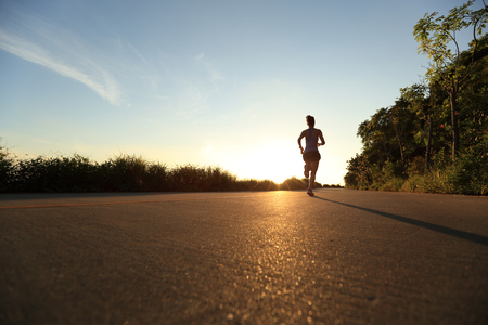 young fitness woman running on sunrise seaside trailの写真素材