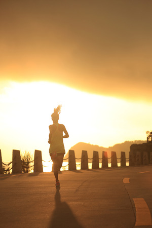 young fitness woman running on sunrise seaside trailの写真素材