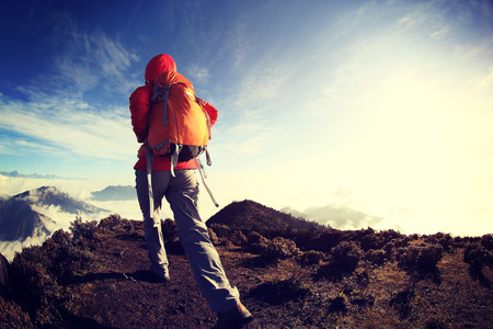 young woman backpacker hiking to beautiful mountain peakの写真素材