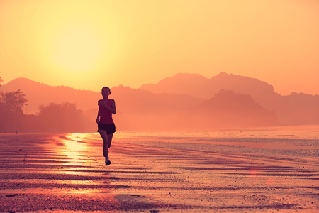 young healthy lifestyle woman running at sunrise beachの写真素材