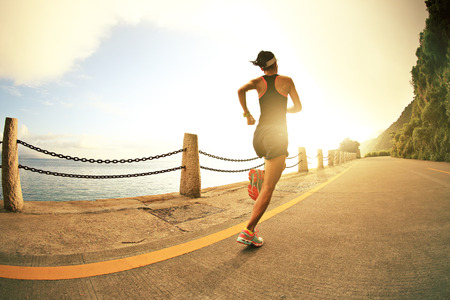 young fitness woman running on sunrise seaside trailの写真素材