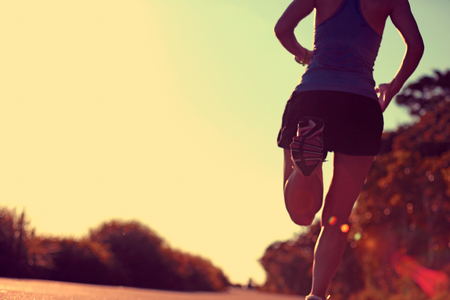 defocused  young fitness woman running on sunrise seaside trailの写真素材