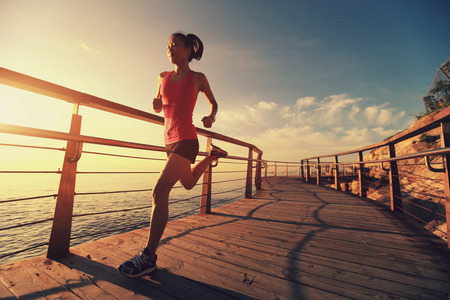 young fitness woman runner running at seaside boardwalkの写真素材