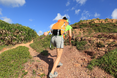 young woman backpacker climbing on seaside mountain trailの写真素材