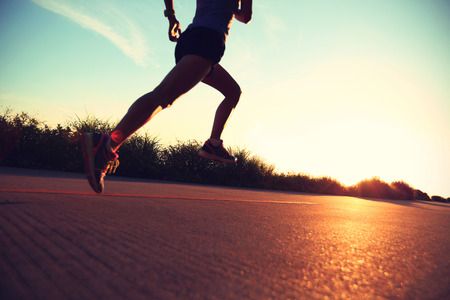 defocused young fitness woman running on sunrise seaside trailの写真素材