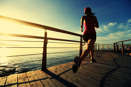 young fitness woman runner running at seaside boardwalkの写真素材