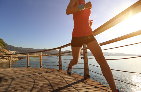 young fitness woman runner running at seaside boardwalkの写真素材