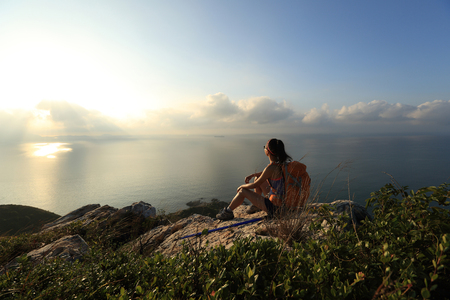 young woman backpacker at sunrise seaside mountain peakの写真素材