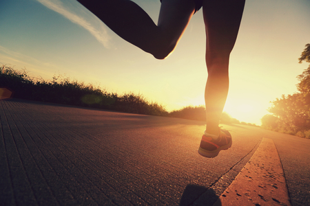 young fitness woman running on sunrise seaside trailの写真素材