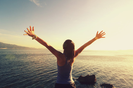 young cheering woman jogger open arms at sunrise seaside,vintage effectの写真素材