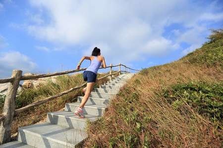 young fitness woman trail runner running up on mountain stairsの写真素材