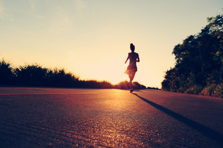 defocused  young fitness woman running on sunrise seaside trailの写真素材
