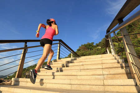 healthy lifestyle sports woman running up on stone stairs seasideの写真素材