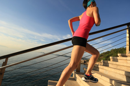 healthy lifestyle sports woman running up on stone stairs seaside
