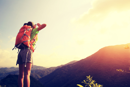young woman backpack yelling at mountain peakの写真素材