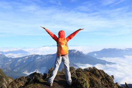 young woman backpacker hiking to beautiful mountain peakの写真素材
