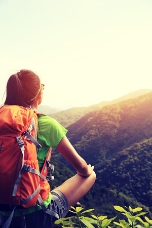 woman backpacker enjoy the view at mountain peak cliffの写真素材
