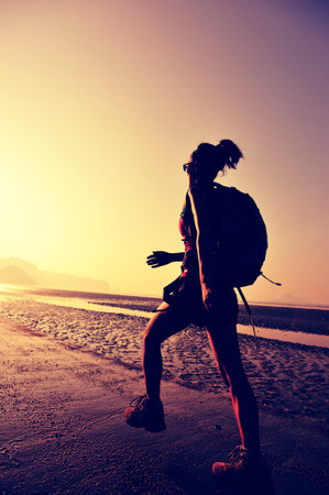 young woman hiker on sunrise beachの写真素材