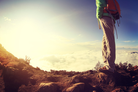 hiker legs on sunset mountain peak enjoy the viewの写真素材