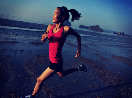 young fitness woman jogging at sunrise beachの写真素材