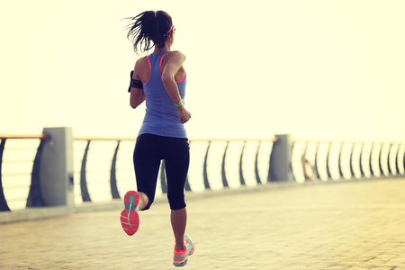 young woman runner athlete running at seasideの写真素材