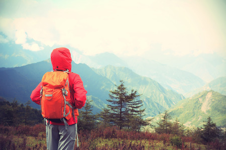 young determined woman backpacker hiking on mountain peakの写真素材