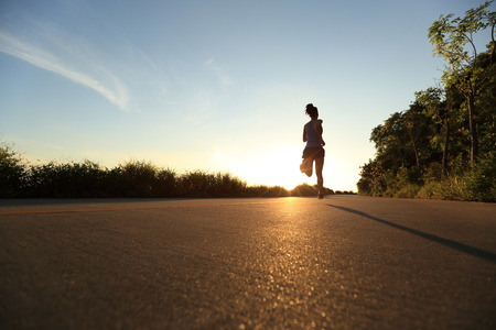 young fitness woman running on sunrise seaside trailの写真素材