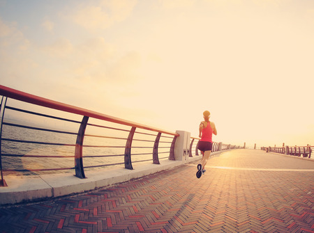 Runner athlete running at seaside. woman fitness silhouette sunrise jogging workout wellness concept.の写真素材