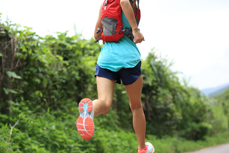 trail runner athlete running on forest trail. woman fitness jogging workout wellness concept.の写真素材