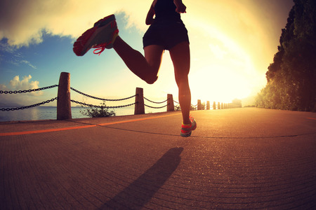 young fitness woman running on sunrise seaside trailの写真素材