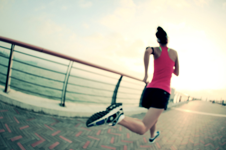 Runner athlete running at seaside. woman fitness silhouette sunrise jogging workout wellness concept.の写真素材