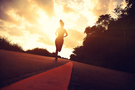 young fitness woman running on sunrise seaside trailの写真素材