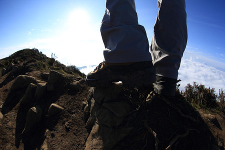 hiker legs on sunset mountain peak enjoy the viewの写真素材