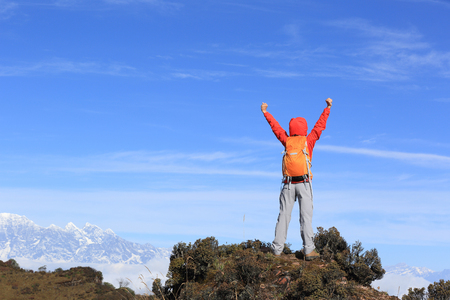 cheering young woman hiker open arms at mountain peakの写真素材