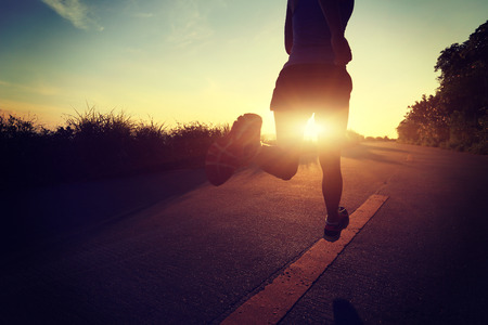 young fitness woman running on sunrise seaside trailの写真素材