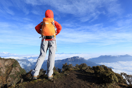 young determined woman backpacker hiking on mountain peakの写真素材