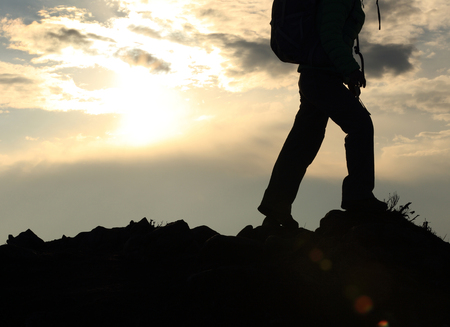 silhouette of backpacker hiking on sunset mountain peakの写真素材