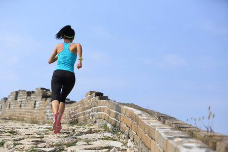 woman runner athlete running on trail at chinese great wall . woman fitness jogging workout wellness concept.の写真素材