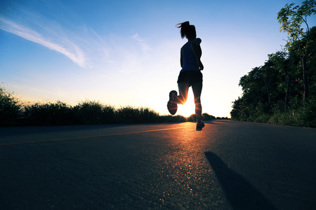 young fitness woman running on sunrise seaside trailの写真素材