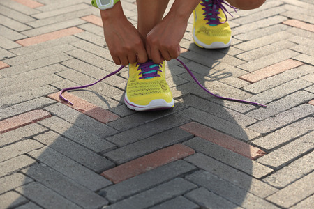 young woman runner tying shoelace outdoorの写真素材