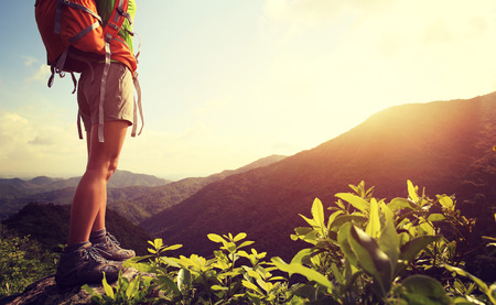 woman backpacker on sunrise mountain peak rockの写真素材