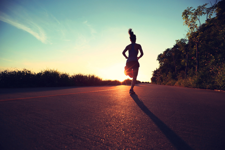 young fitness woman running on sunrise seaside trailの写真素材