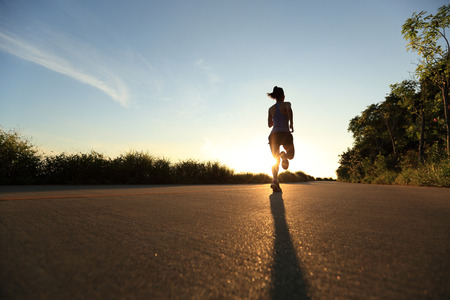 young fitness woman running on sunrise seaside trailの写真素材