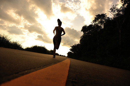 young fitness woman running on sunrise seaside trailの写真素材